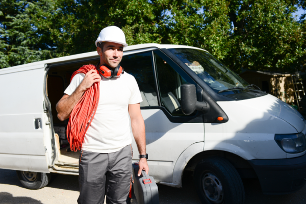 Young electrician taking tools out of his van