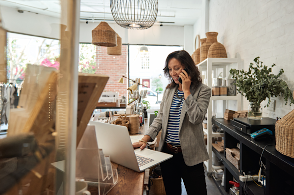 Smiling woman standing behind laptop in retail store