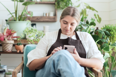 Plant shop owner sitting and looking down at her phone