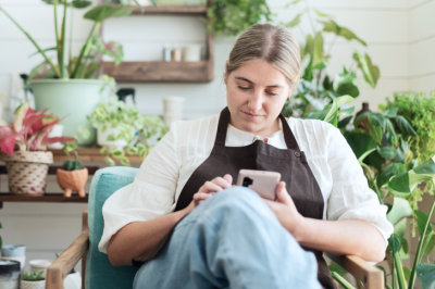 Plant shop owner sitting and looking down at her phone