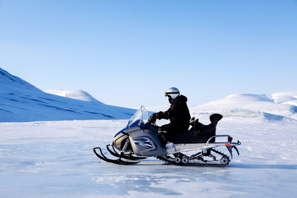 A person on their snowmobile driving through the snow