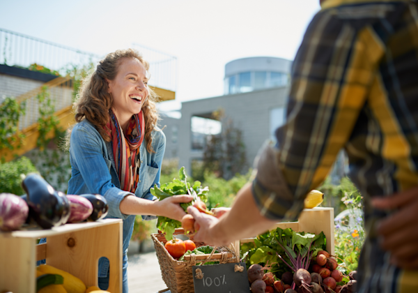 Friendly woman tending an organic vegetable stall at a farmer's market