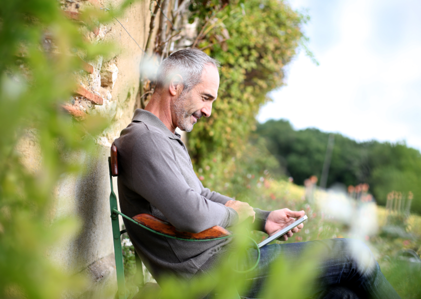 A man relaxing outdoors, looking down at his phone