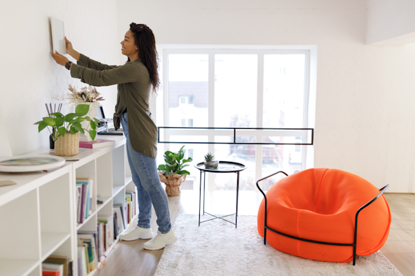 Woman hanging a picture on the wall in a den
