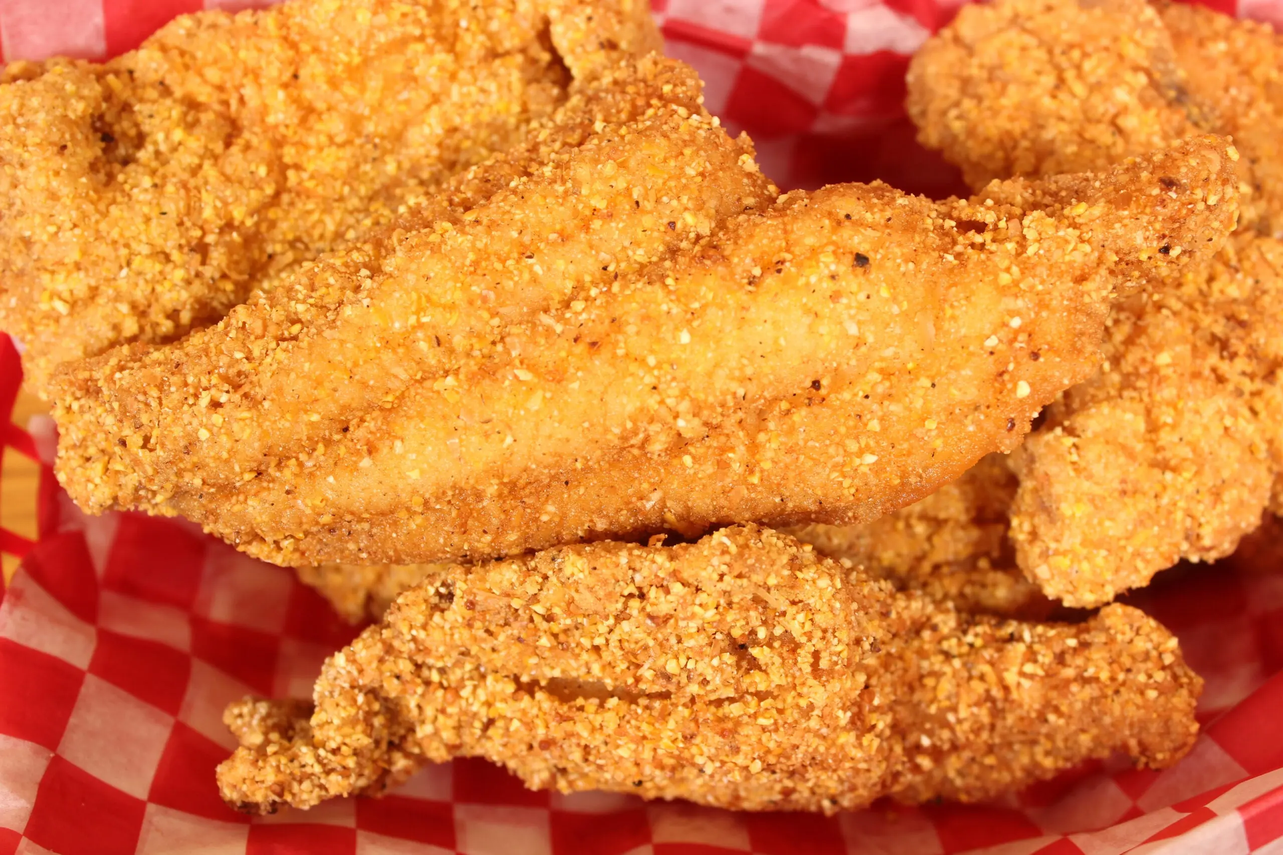 golden brown fried catfish fillets in a basket