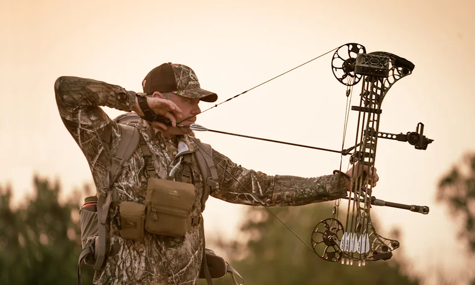 An archer shoots a compound bow into a paper tuning jig.