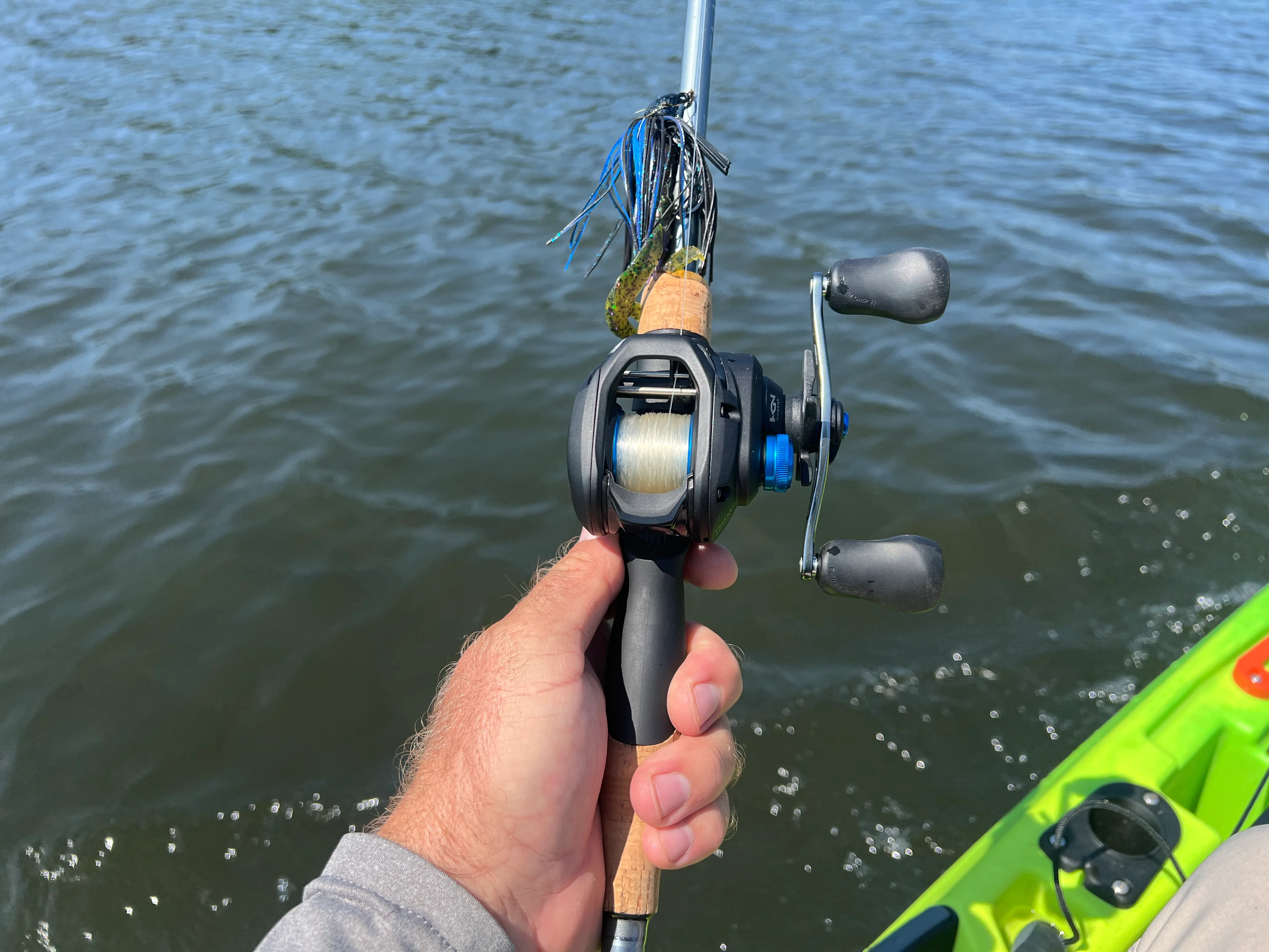 Angler's hand holding Shimano SLX A 150 casting reel.