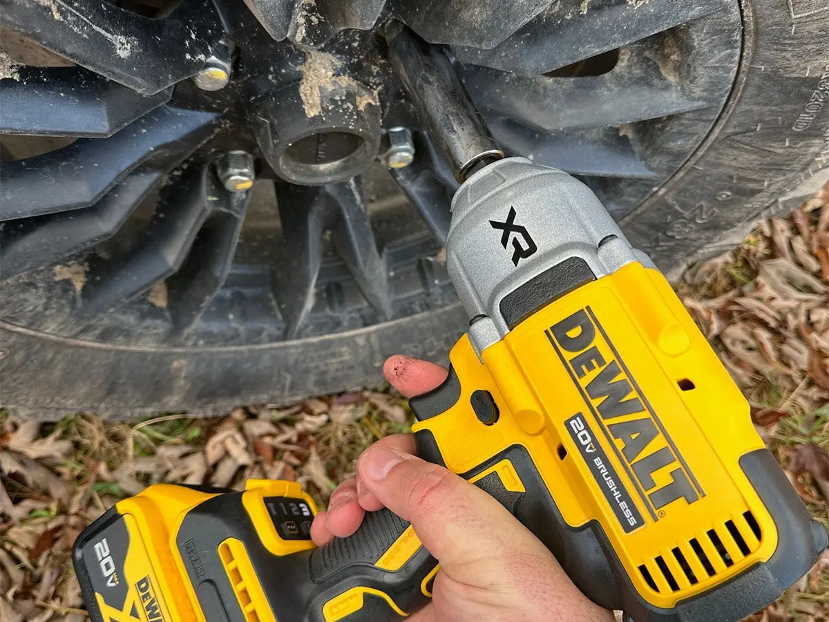 An impact wrench loosening the lug nut of a Honda UTV tire