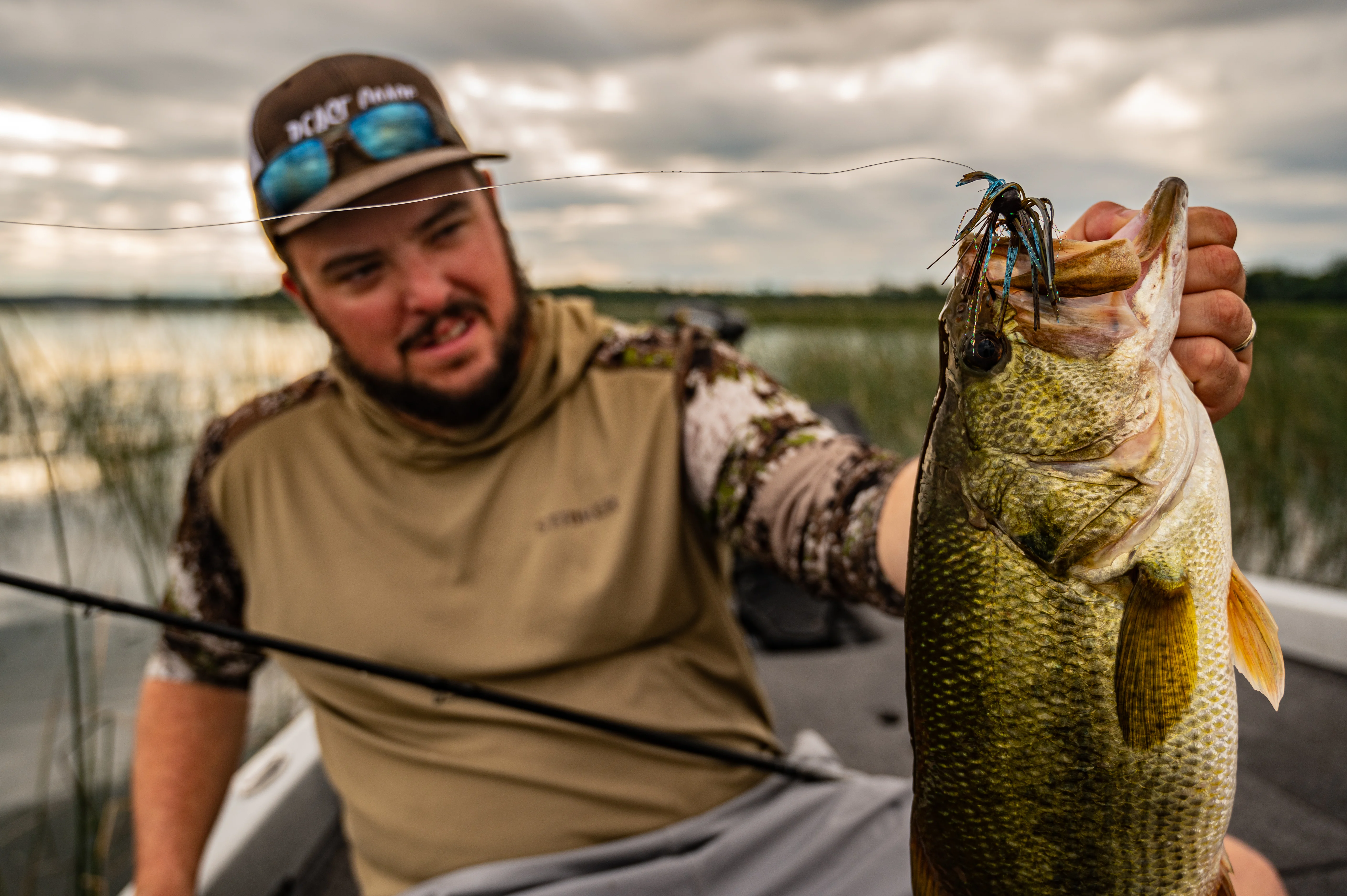 angler holding up largemouth with jig in mouth