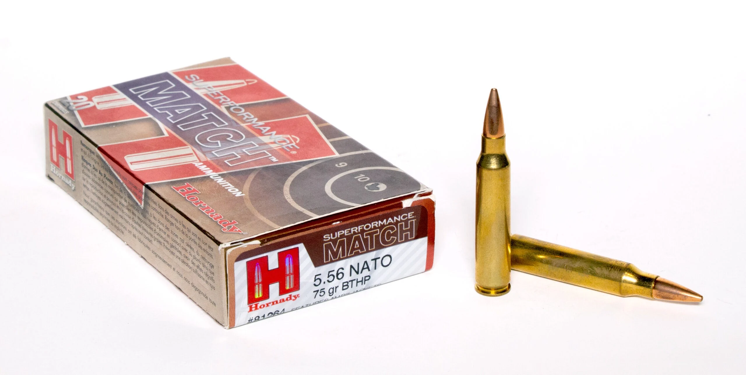 A box of Hornady 556 ammo on white background with two loose cartridges nearby