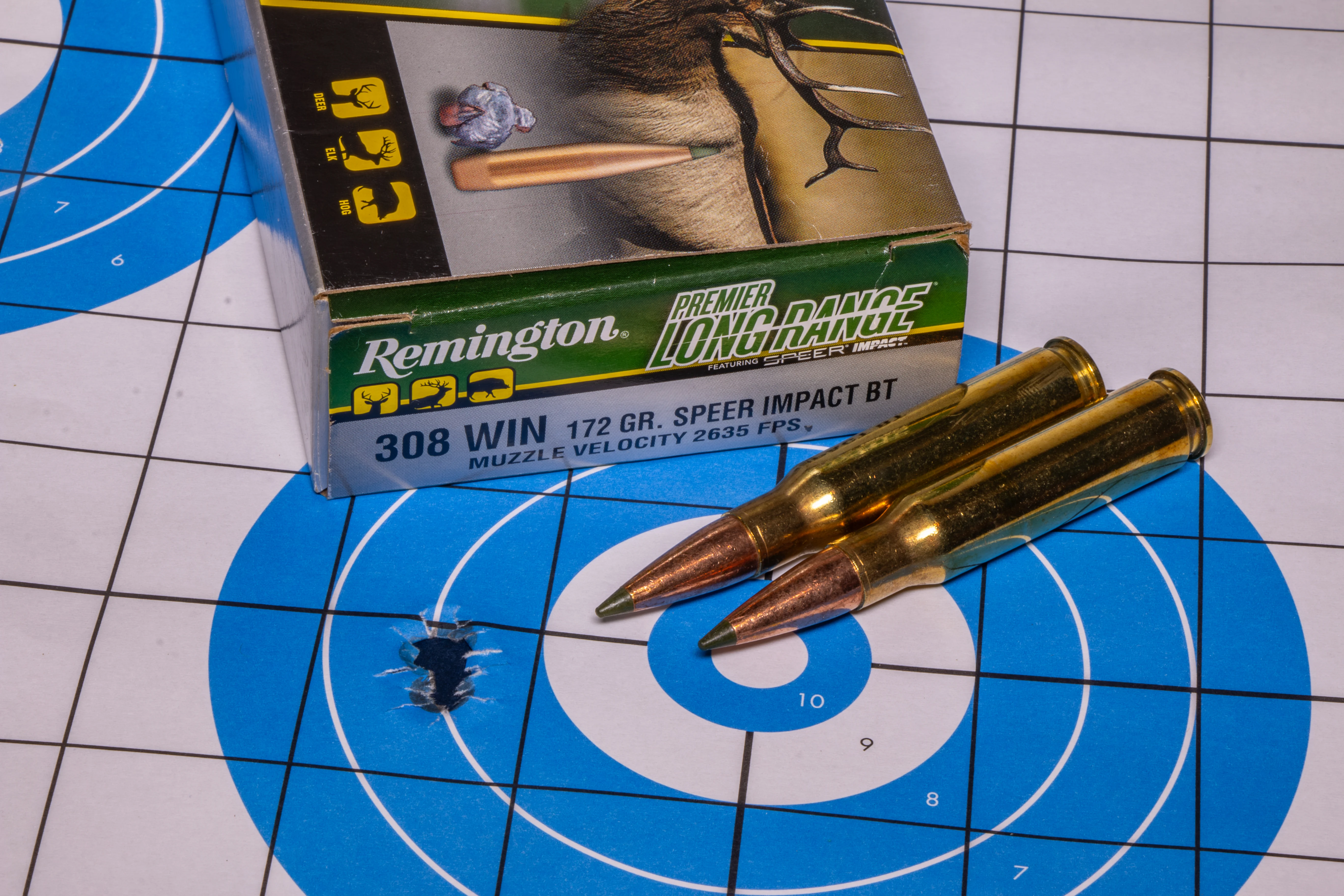 A rifle targer showing a very small group of bullet holes, with Remington ammo nearby.