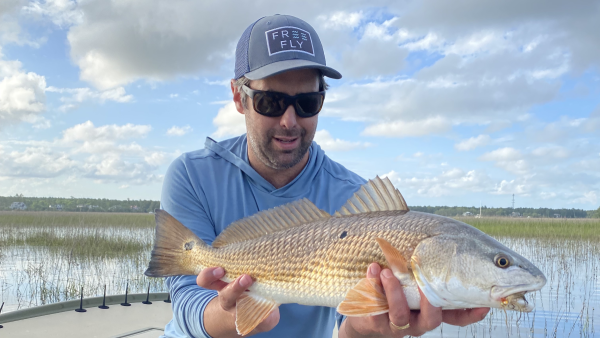 Tanner Sutton, founder of Free Fly, holding a fish on the water