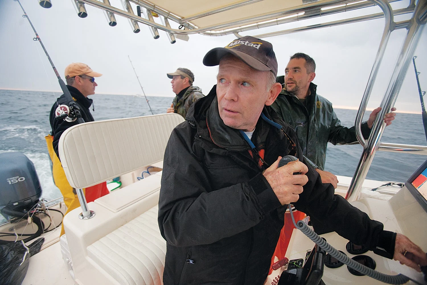 four men at back of fishing boat look back at approaching storm