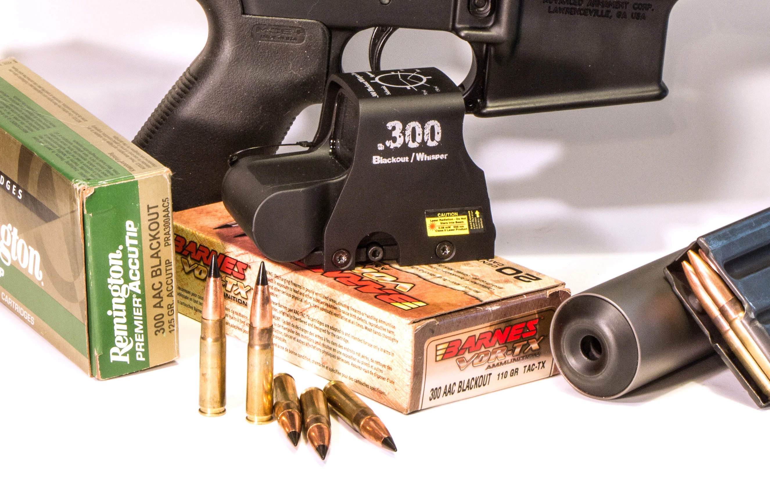 Two boxes of 300 Blackout ammo beside a suppressor, a magazine, and a red-dot sight.