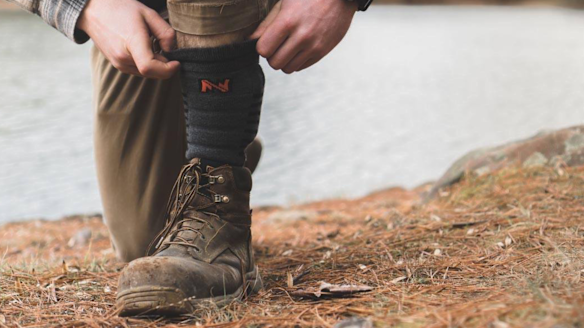 Man pulling up Fieldsheer Wool Heated Socks under hiking boot