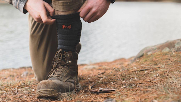 Man pulling up Fieldsheer Wool Heated Socks under hiking boot