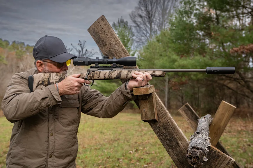 A man shooting for accuracy with a rifle resting on a barricade.