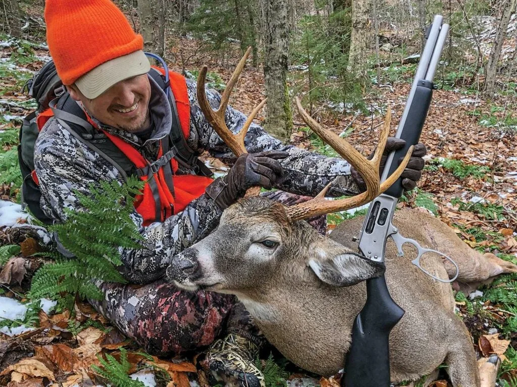 A hunter holds a deer's head by the antlers.