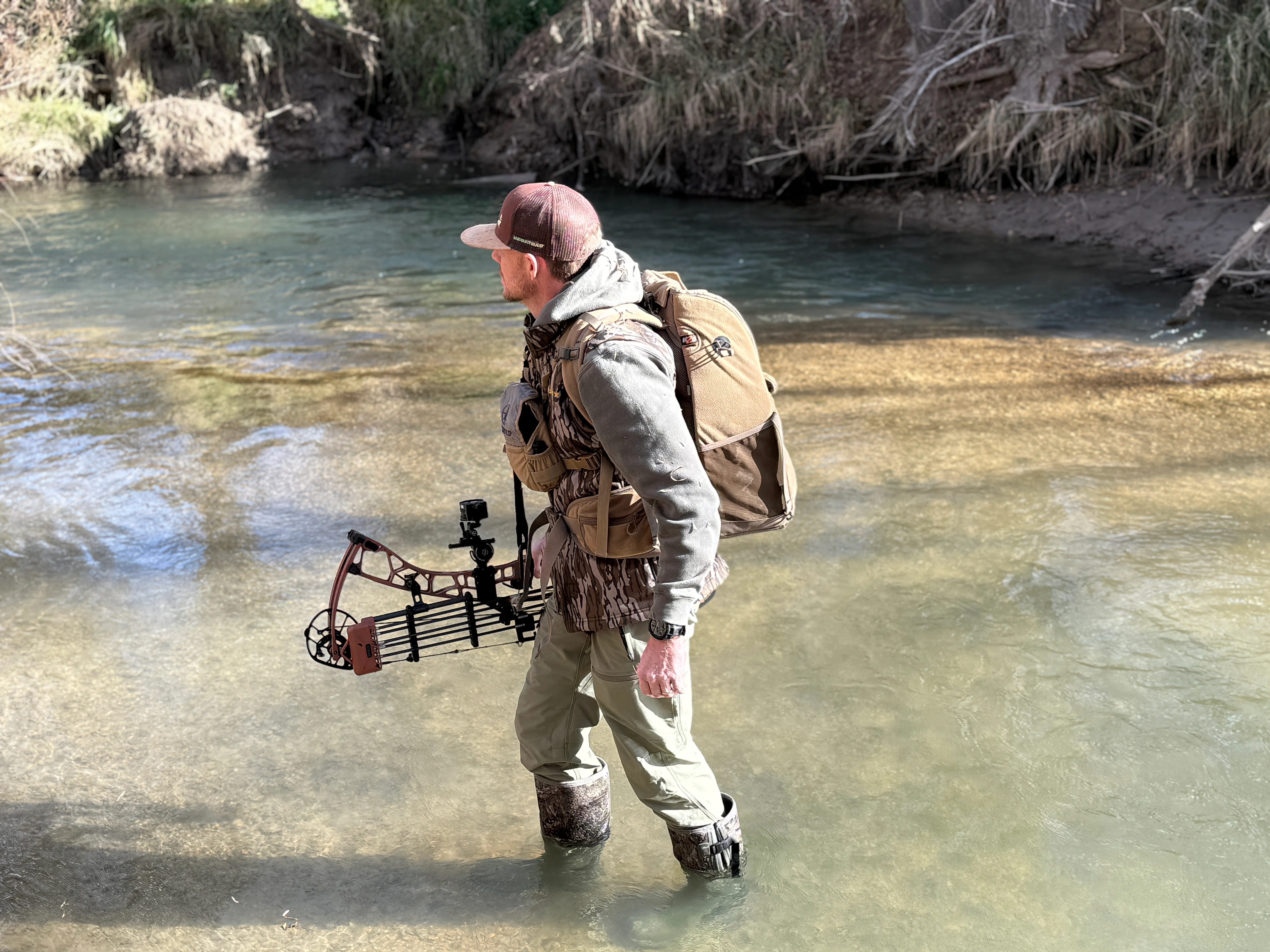 A bowhunter crosses a creek to get to his tree stand. 