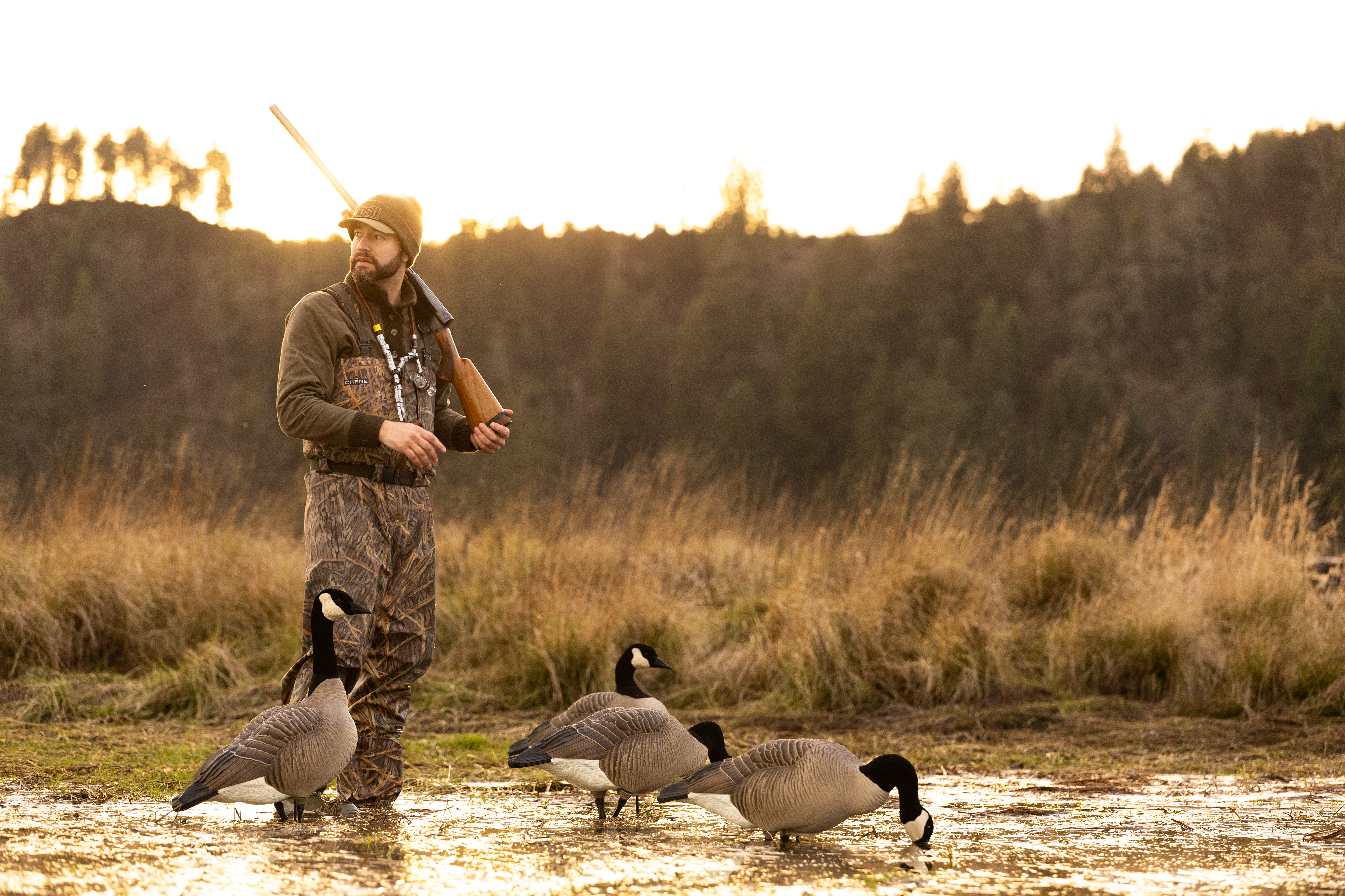 Hunter standing in water with gun on shoulder