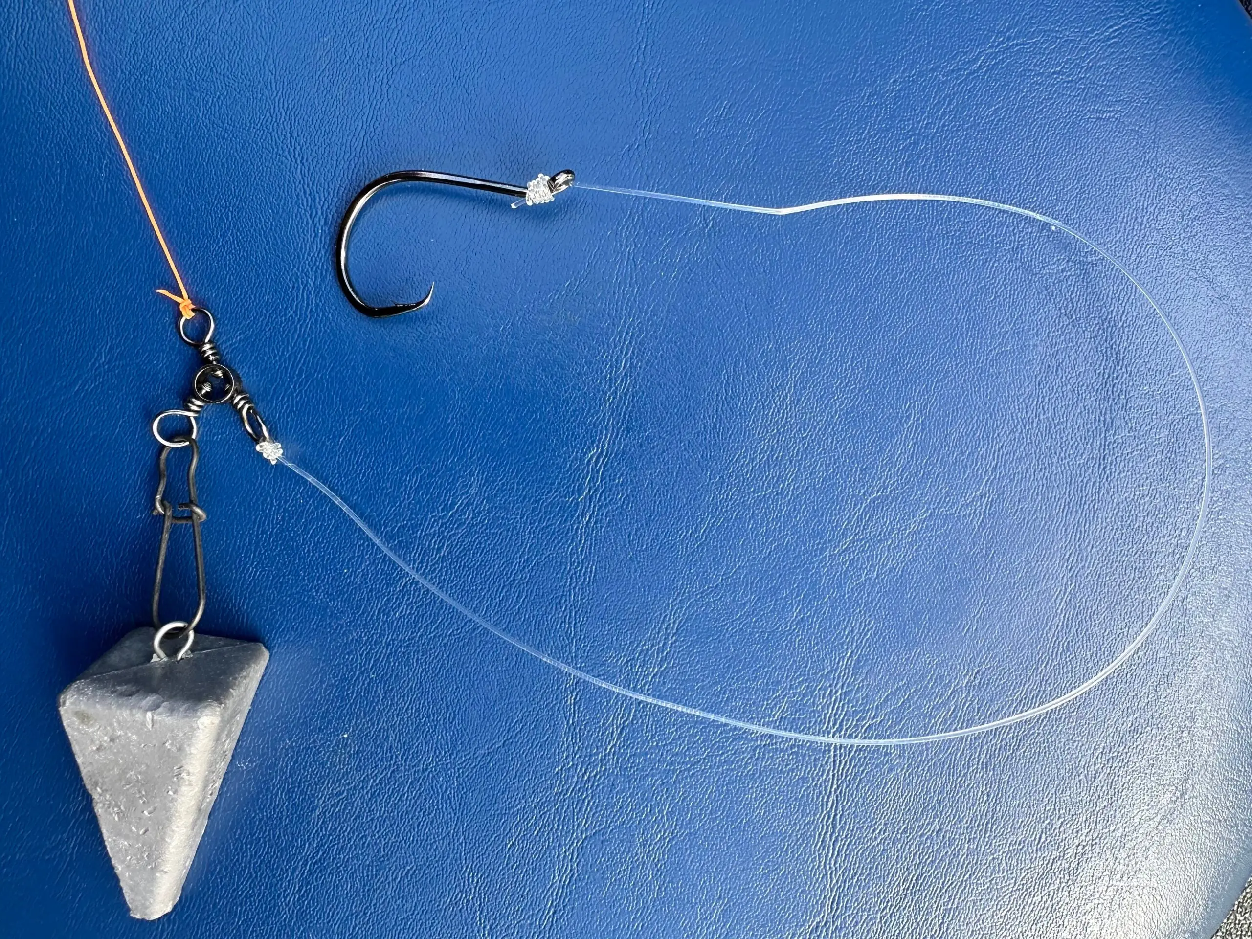 A standard surf fishing rig with a pyramid sinker, circle hook, and fishing line on a blue background