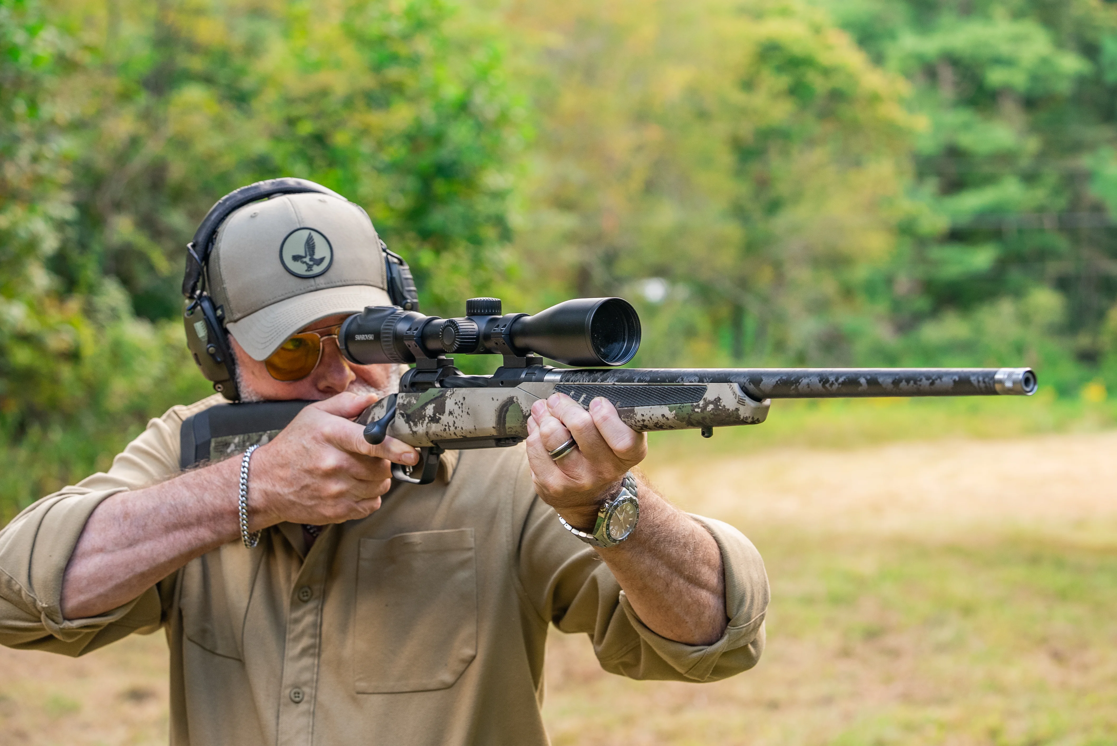 A shooter fires the new Savage 110 Ultralite from offhand in a field.