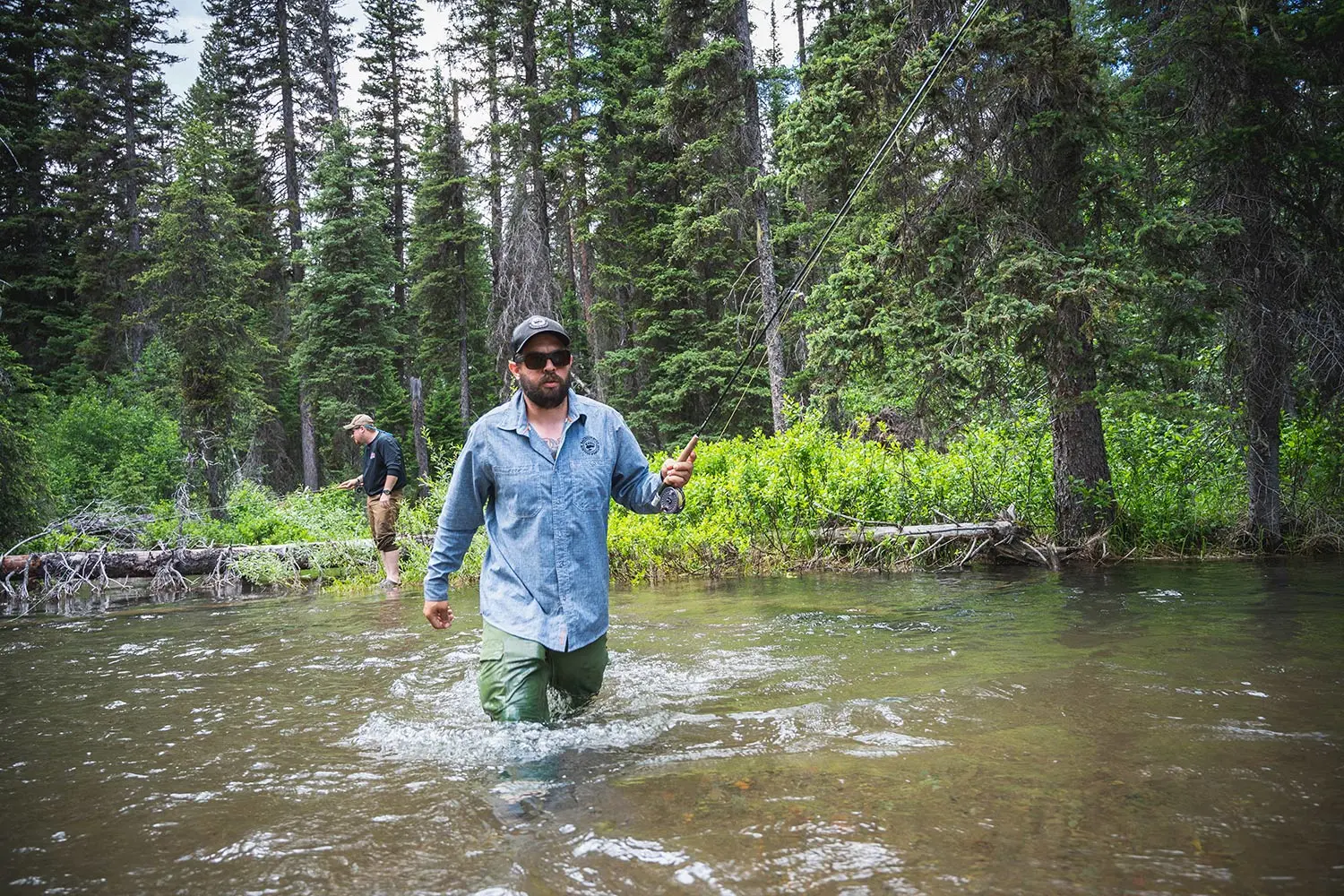 Angler crosses stream holding fly rod