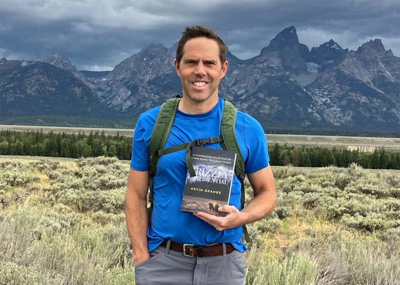 Author Kevin Grange poses with a photo of his latest book, Grizzly Confidential.