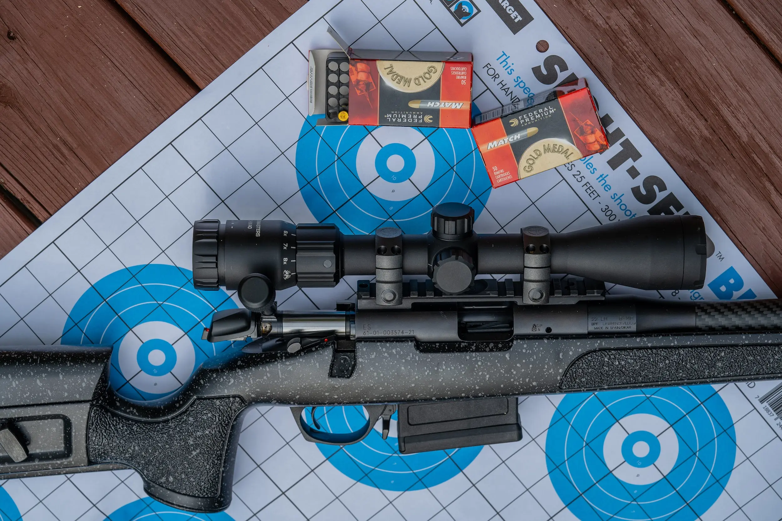 Rifle with a scope sitting on a table.