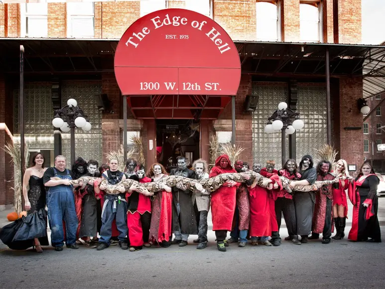 A group of people in costumes holds up a large reticulated python