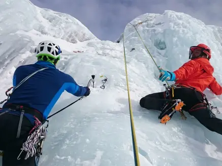 Two ice climbers climb up a wall.