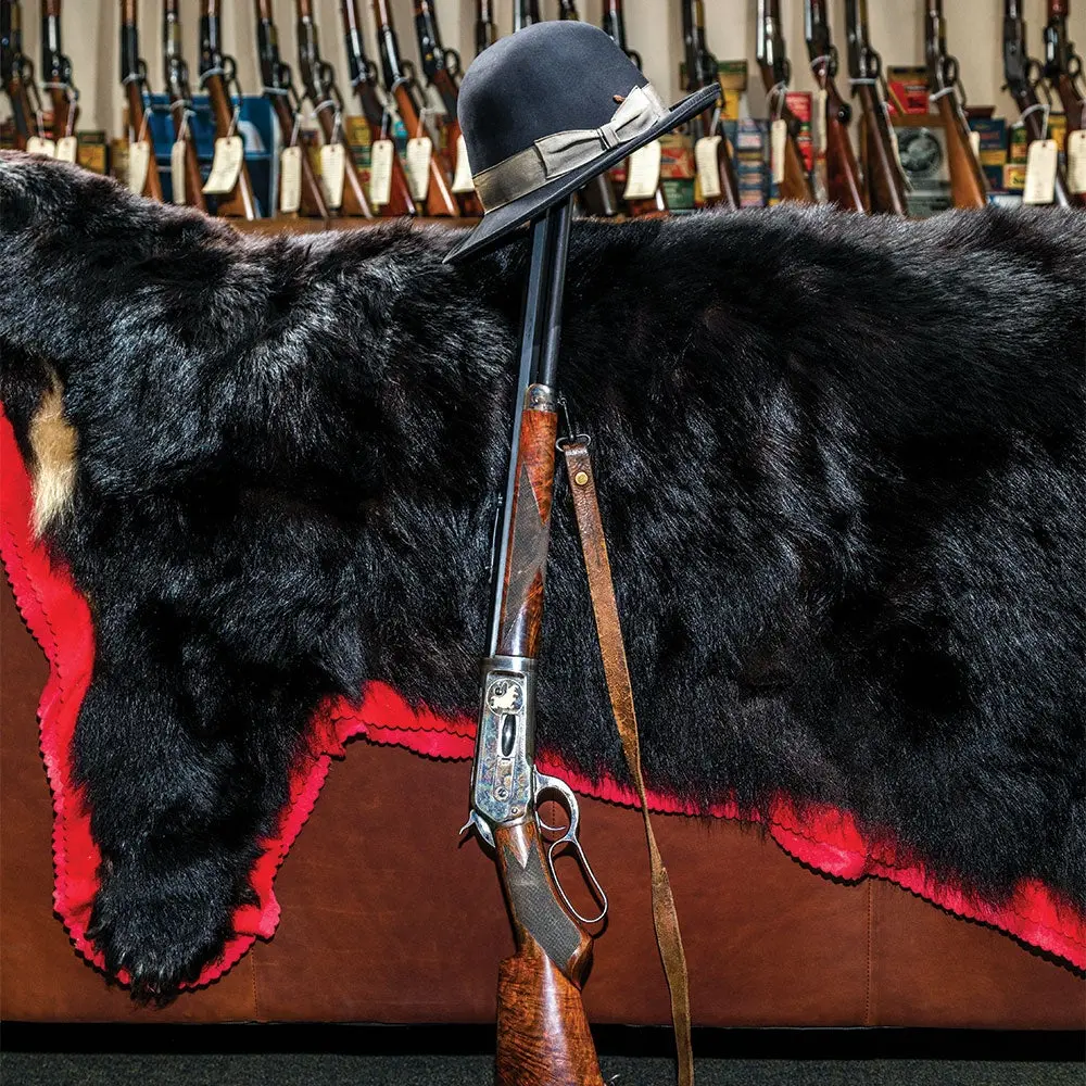 a winchester lever action rifle leaning against a bear pelt