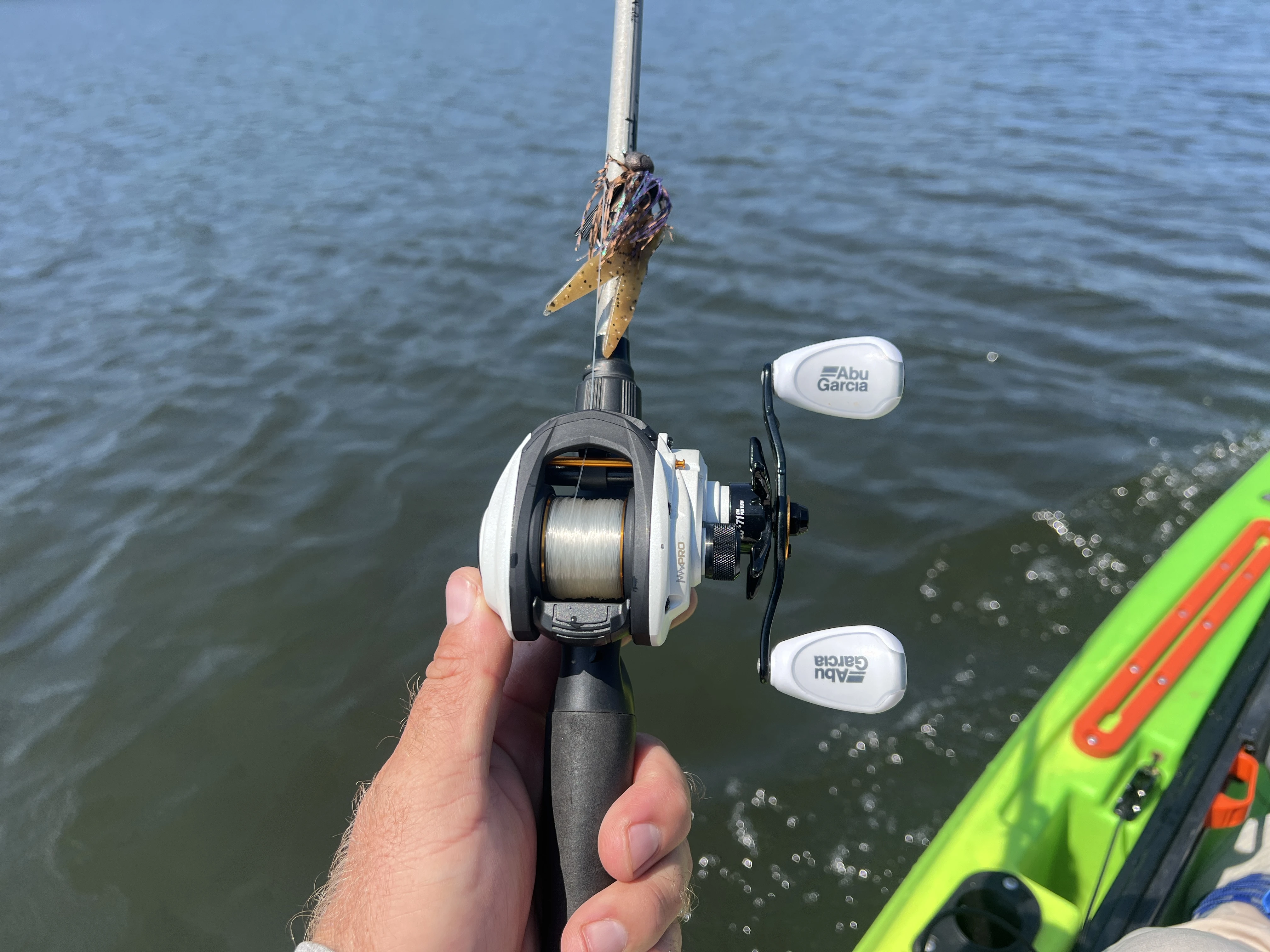 Angler's hand holding fishing reel in kayak