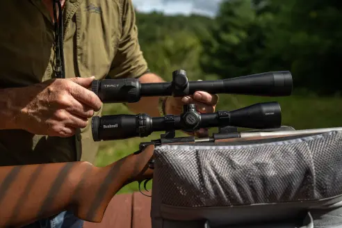 Two rimfire scopes next to each other on a shooting bench.