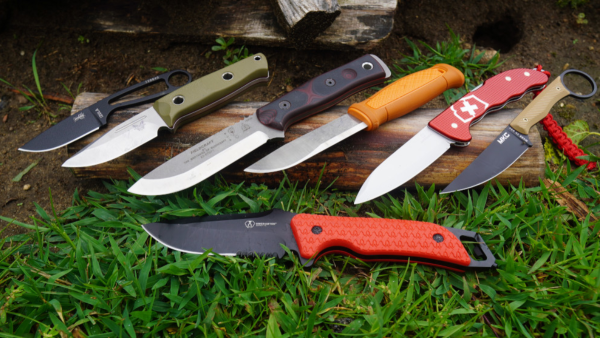 Assorted best survival knives laying on grass