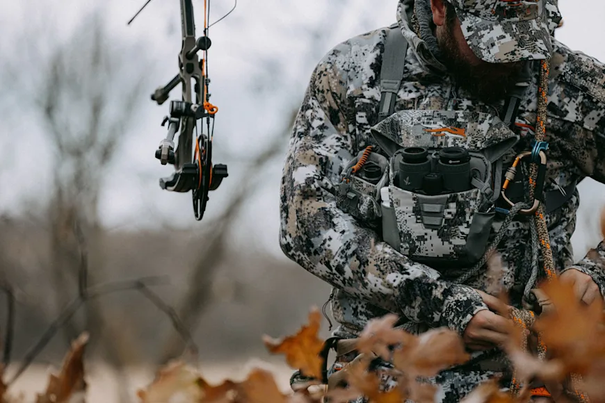 A tree stand hunter puts on a Sitka bino harness.
