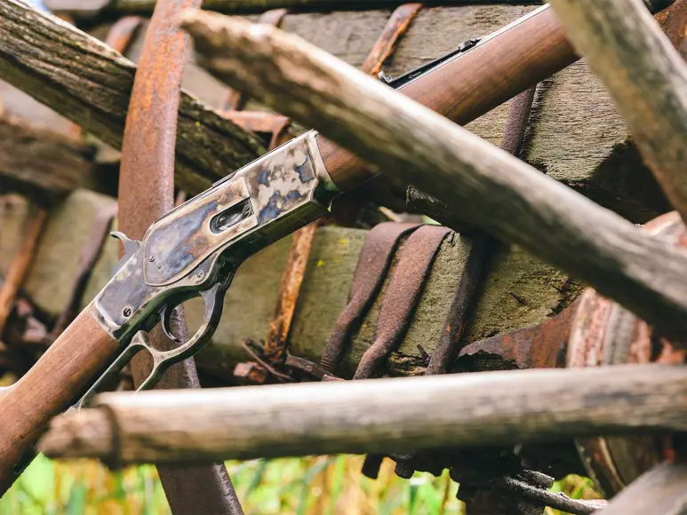 A Winchester rifle leaning against a wooden wagon.