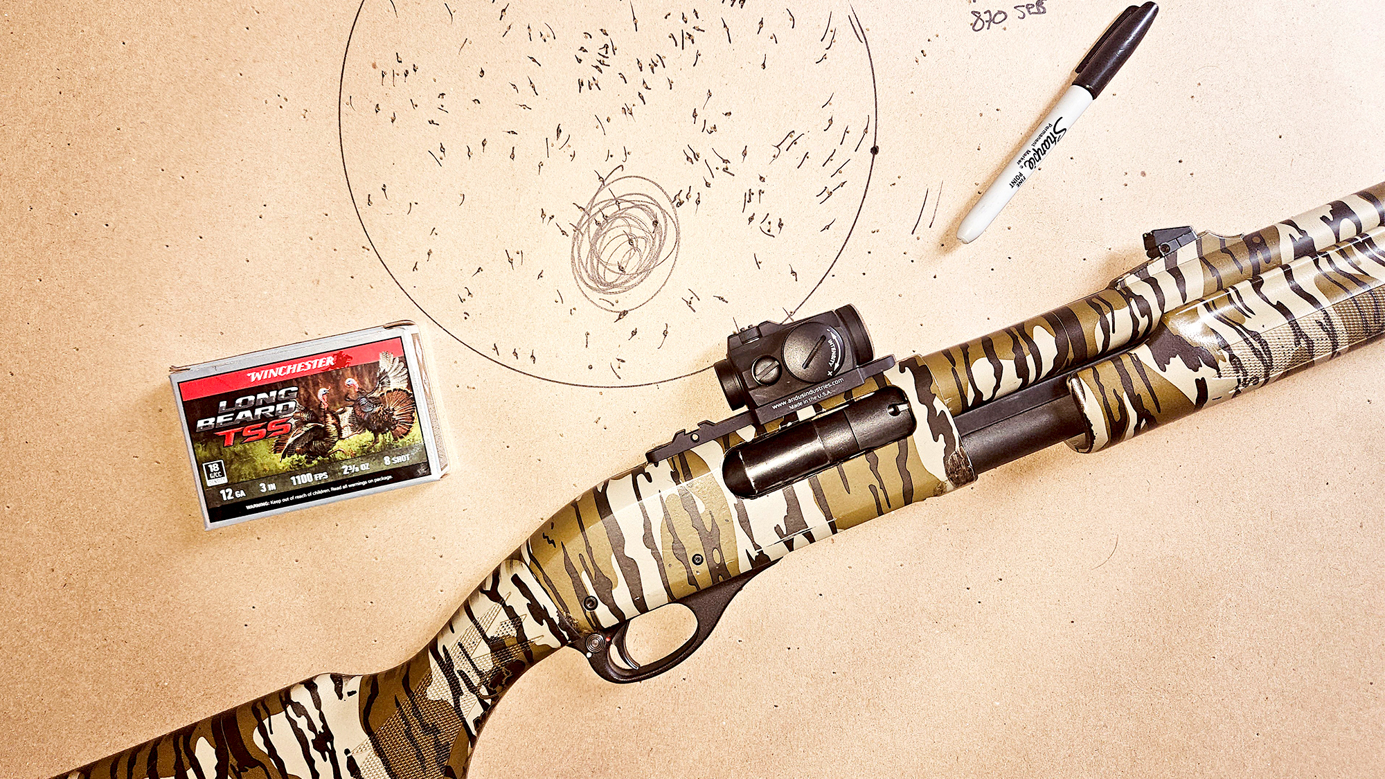 A shotgun and shells on a piece of paper used for patterning the gun. 