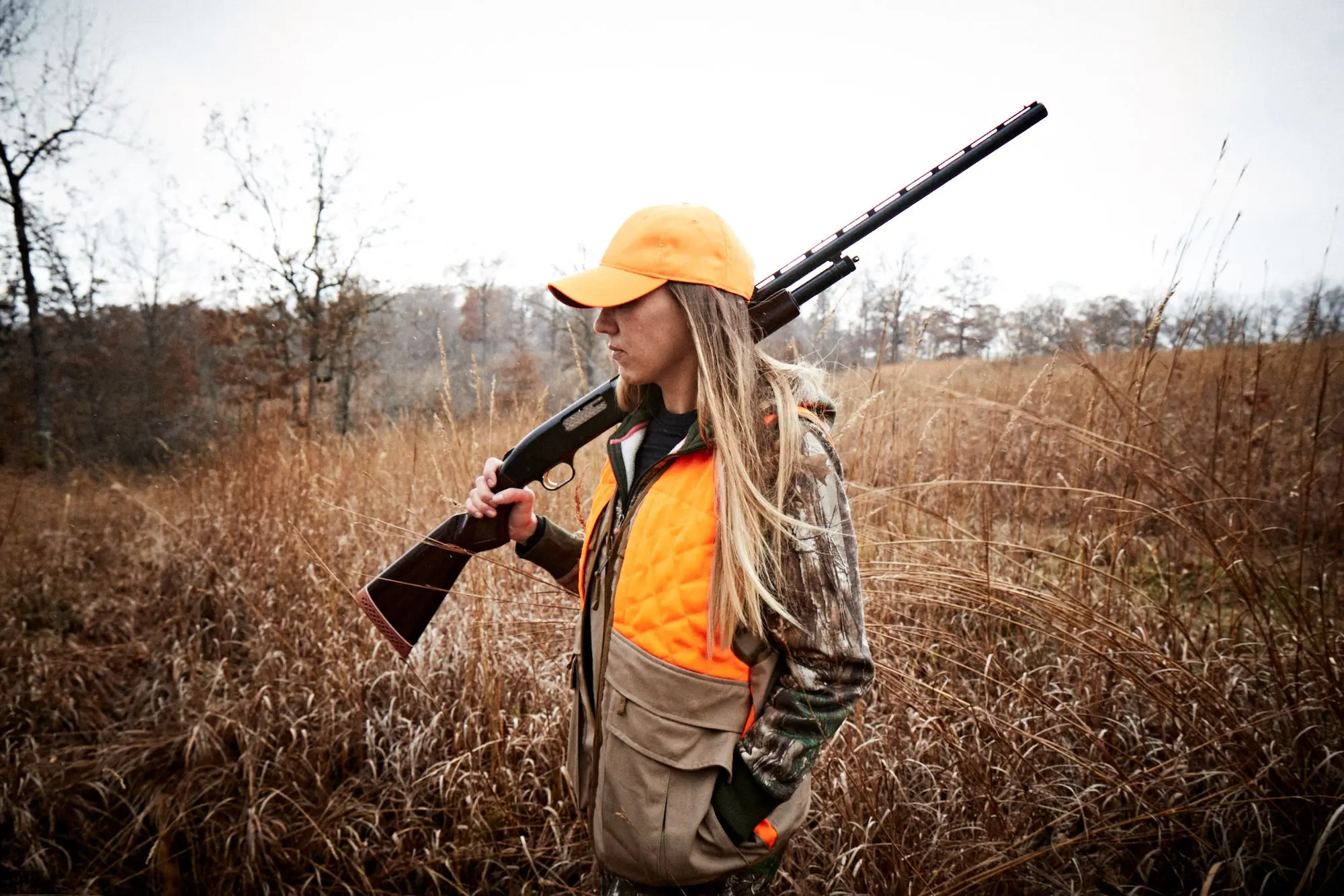 hunter carrying a mossberg 500 in a field.