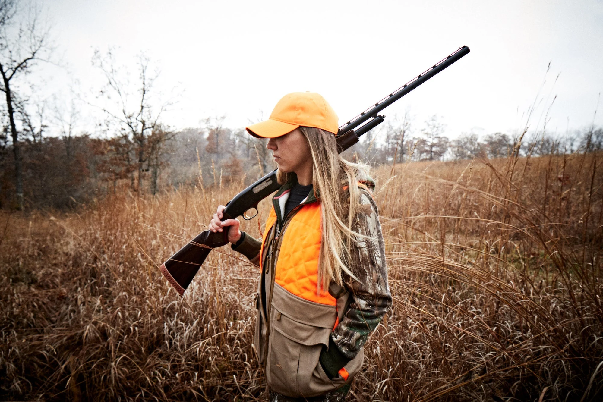 hunter carrying a mossberg 500 in a field.