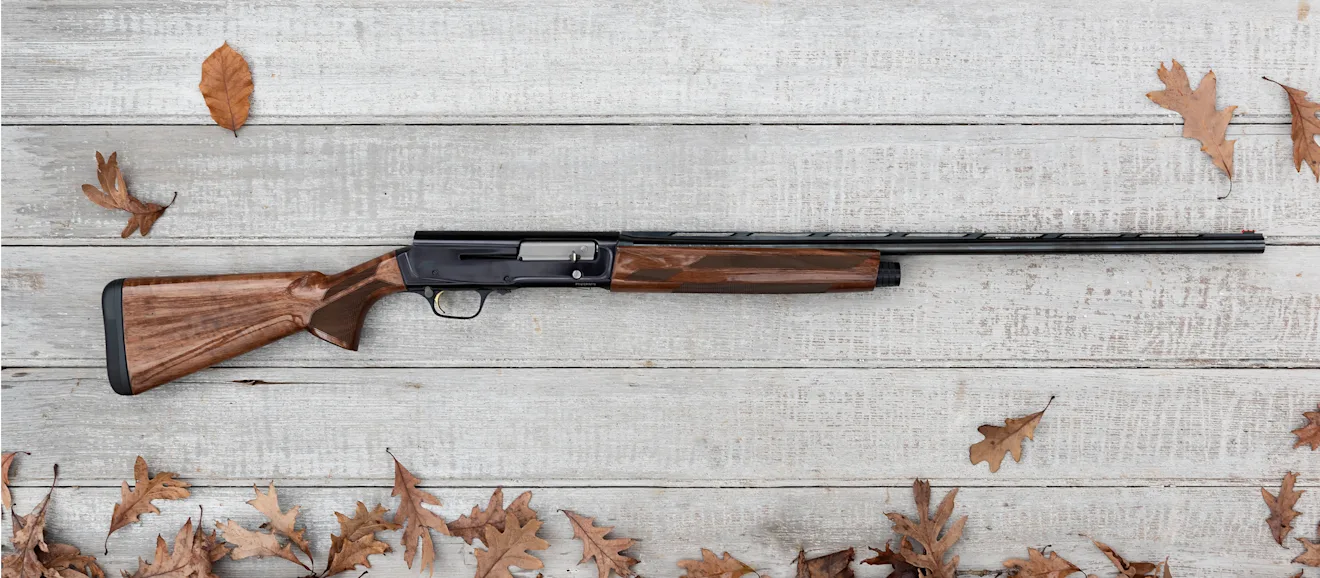 Browning A5 Hunter 20-gauge on a wood background with some fall leaves scattered.
