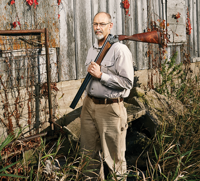 A man holds a shotgun over his shoulder.