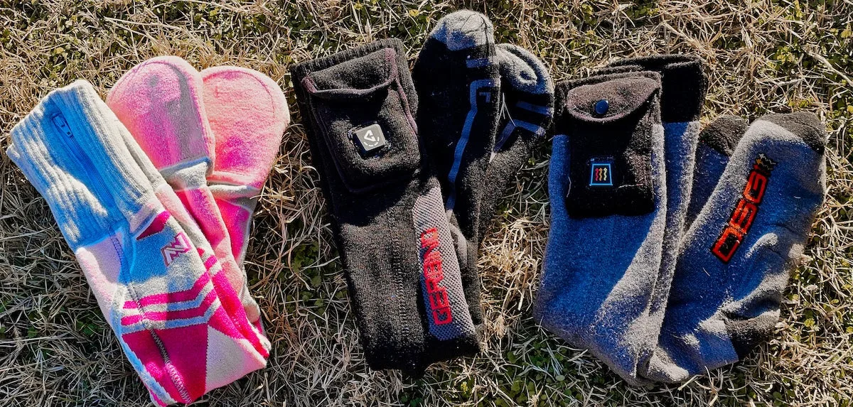 Three pairs of heated socks lined up on the grass during testing