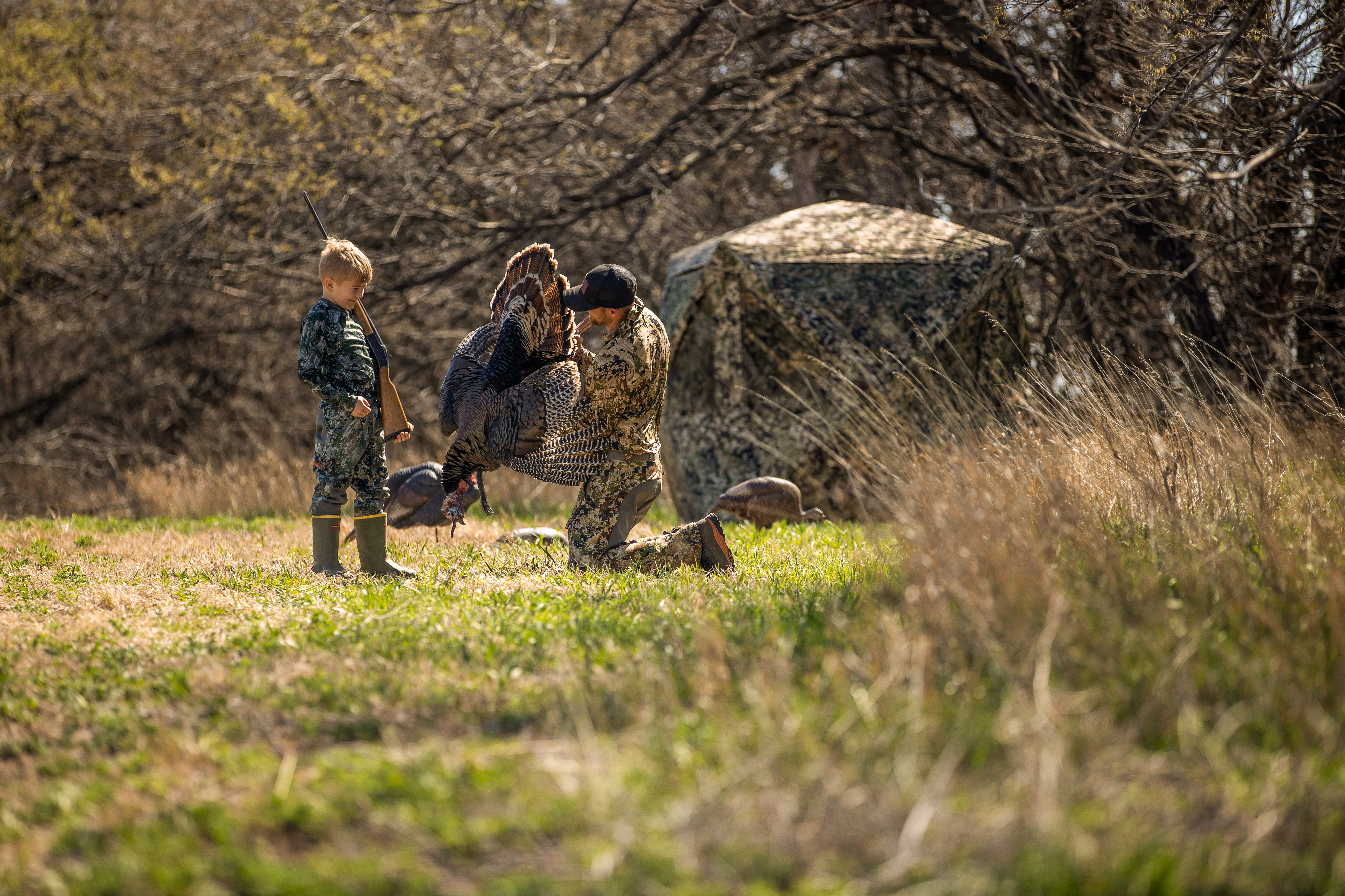 A father and son celebrate a successful turkey hunt.