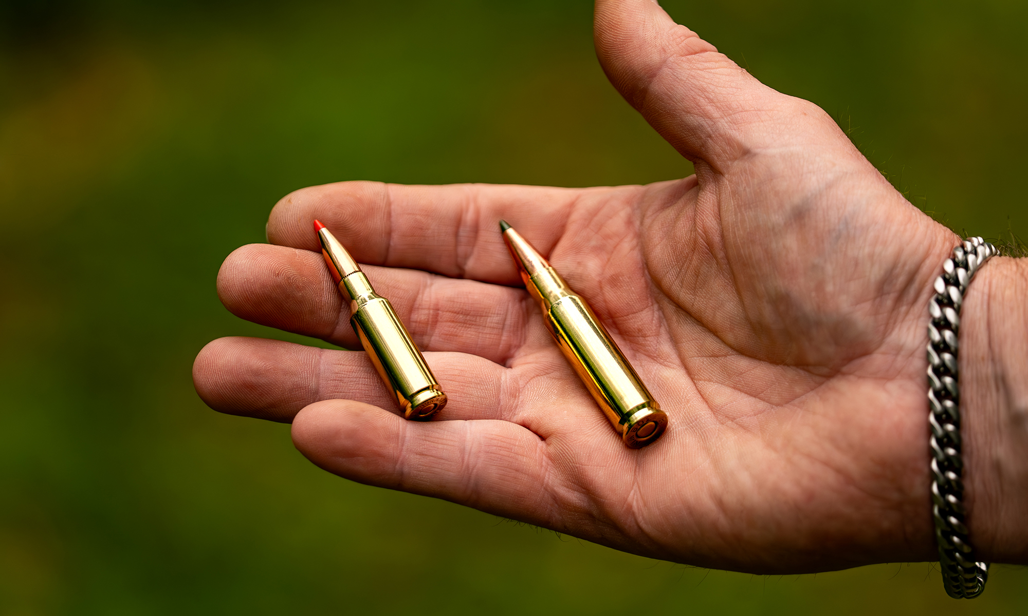 6.5 Grendel vs 308 Winchester, one of each cartridges in a shooter's hand.