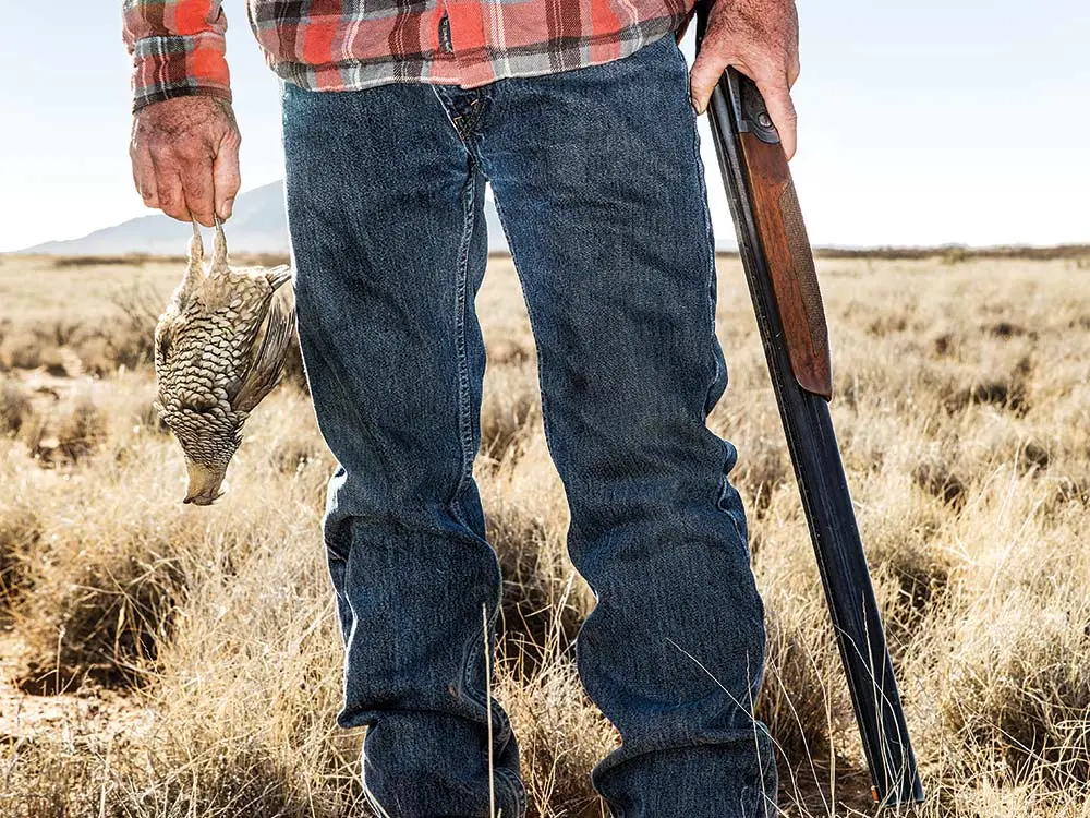 hunter holding shotgun and quail