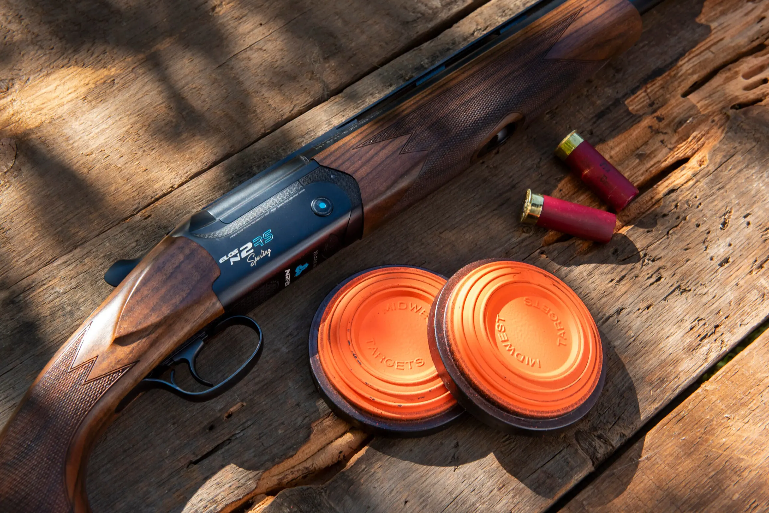 Close-up of new Fabarm Elos D2 RS over/under shotgun on a table with shells and two clay targets