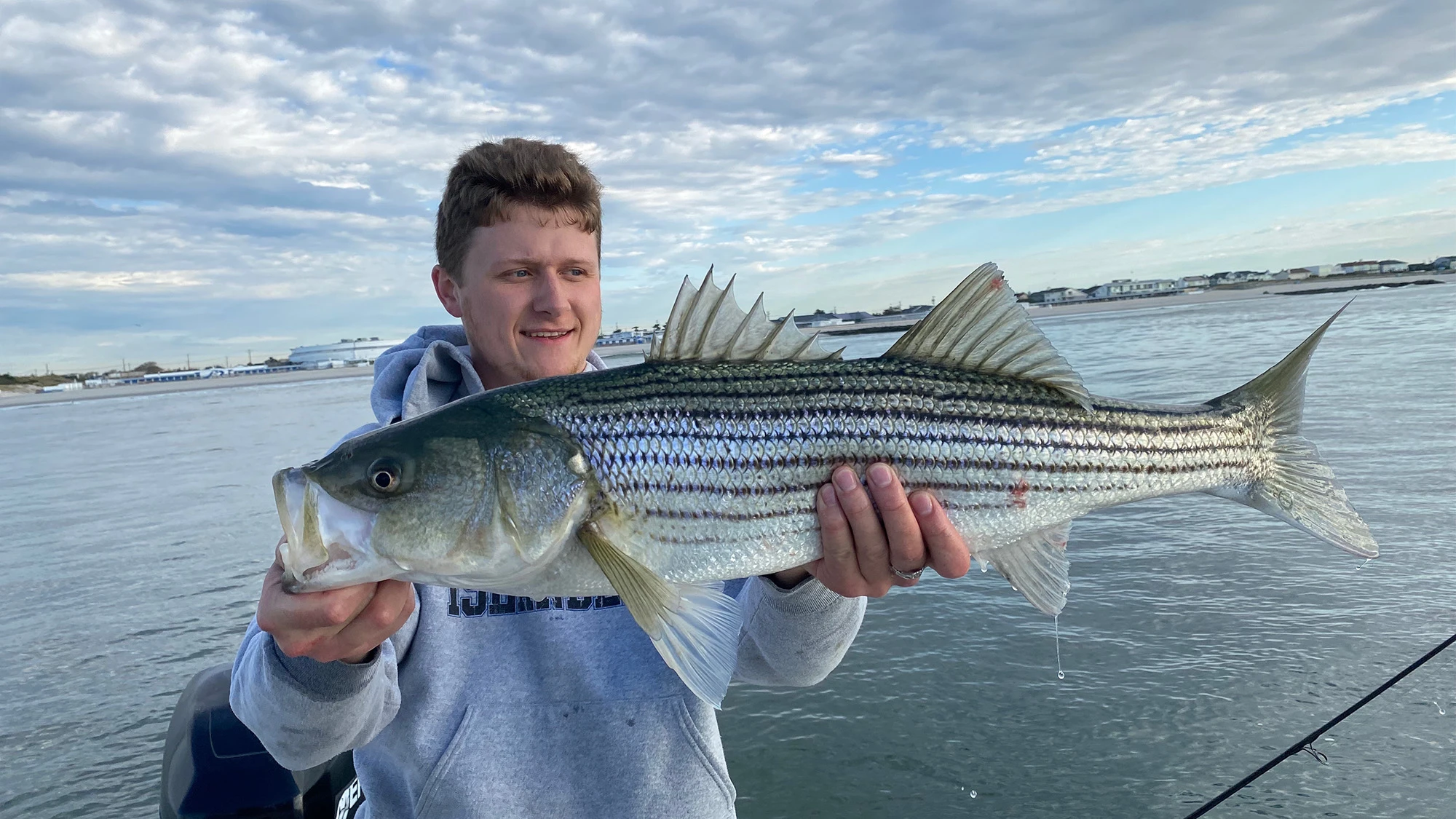 Angler holding up striped bass on a boat