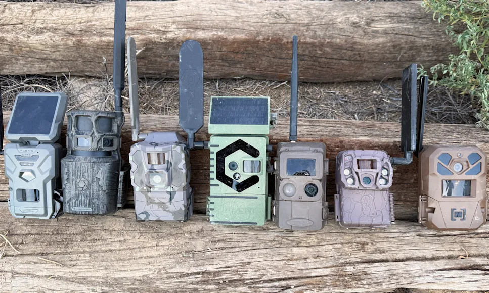 Six new cellular trail camera line up on a log.