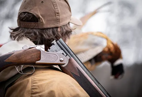 Hunter with a shotgun over his shoulder.